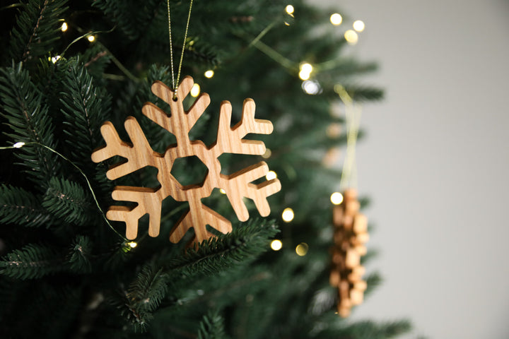 Natural-ash-wood-snowflake-ornament-with-detailed-carving-and-smooth-finish