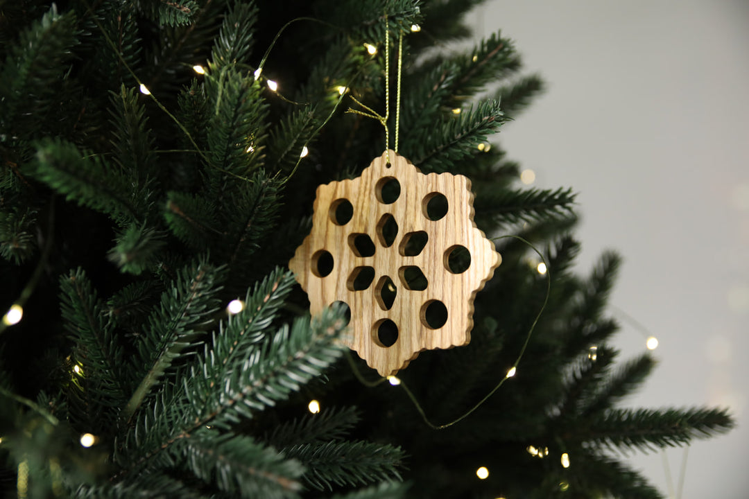 Natural-ash-wood-snowflake-ornament-with-detailed-carving-and-smooth-finish