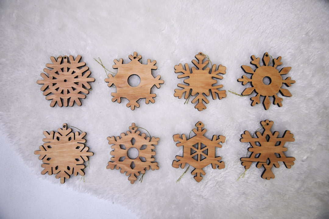 hands-holding-wooden-snowflake-ornaments-near-a-Christmas-tree-with-lights
