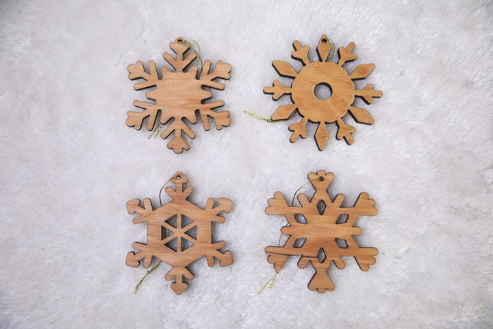 hands-holding-wooden-snowflake-ornaments-near-a-Christmas-tree-with-lights